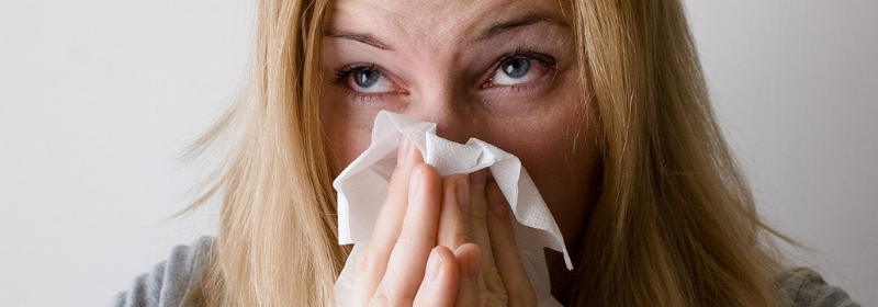 woman with histamine intolerance blowing nose with tissue