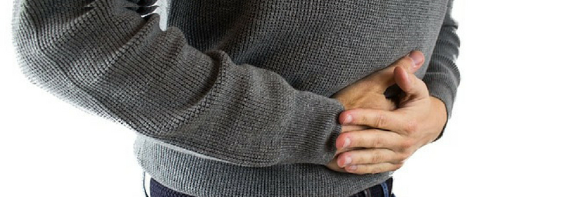 man holding hands on stomach due to salicylate intolerance