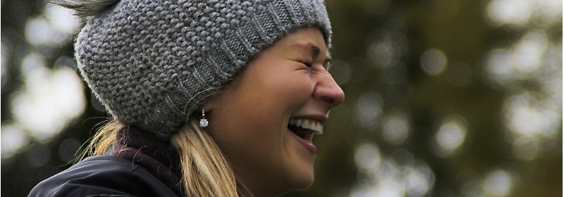 woman without hay fever in winter laughing outside in beanie
