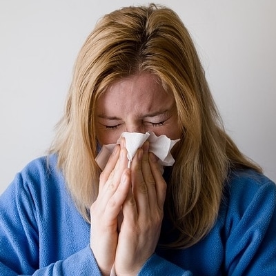 woman with hay fever or cold blowing nose