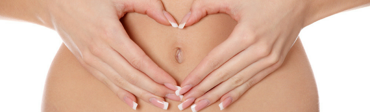 woman with hands over stomach in love heart after having natural treatment for IBS and food intolerance