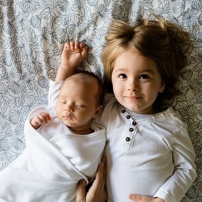 child with baby brother lying on bed