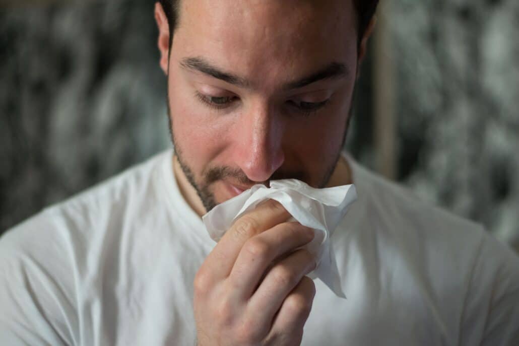 man blowing his nose due to hay fever